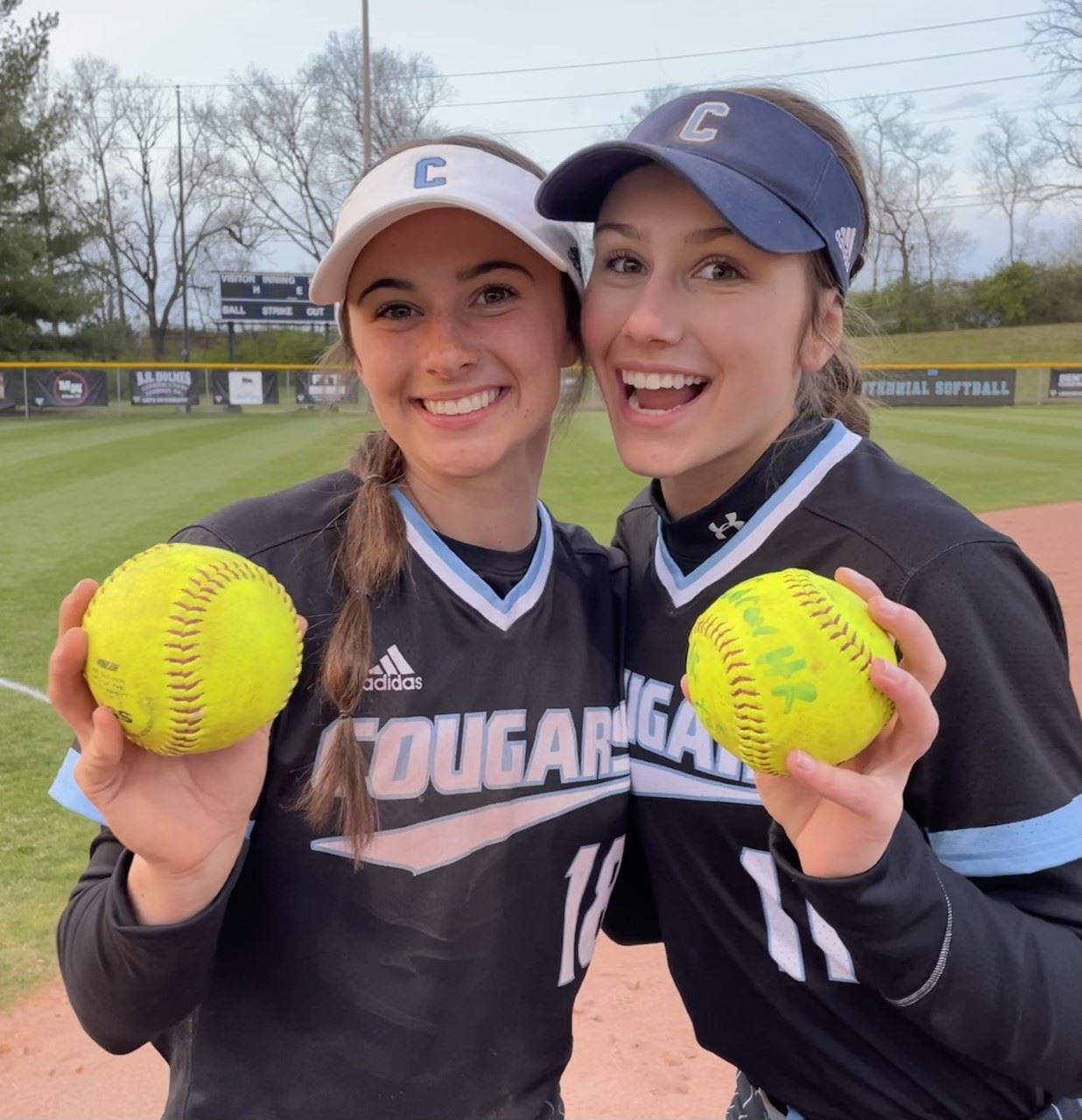 Two softball players each holding a softball