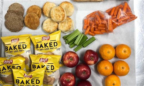 Overhead shot of sausage, chicken, biscuits, fruit and vegetables and chips