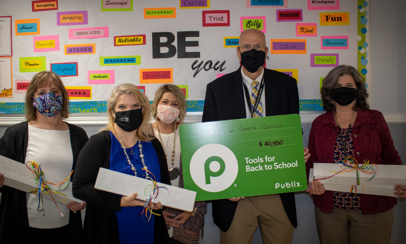 people pose with boxes and a cardboard check 