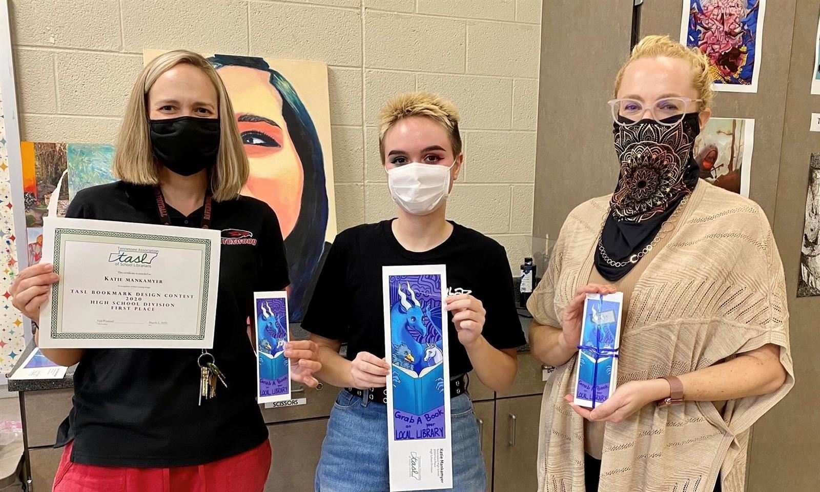 Students and teacher hold up a contest-winning bookmark 