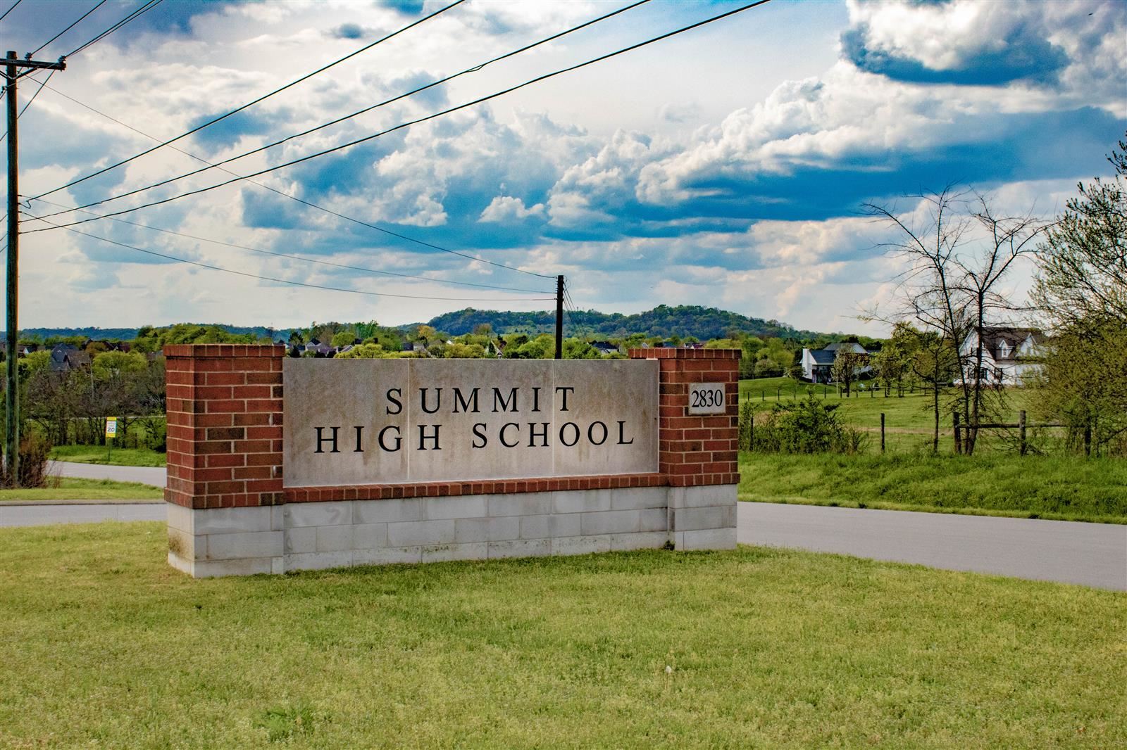 Summit High School sign in front parking lot on clear day.