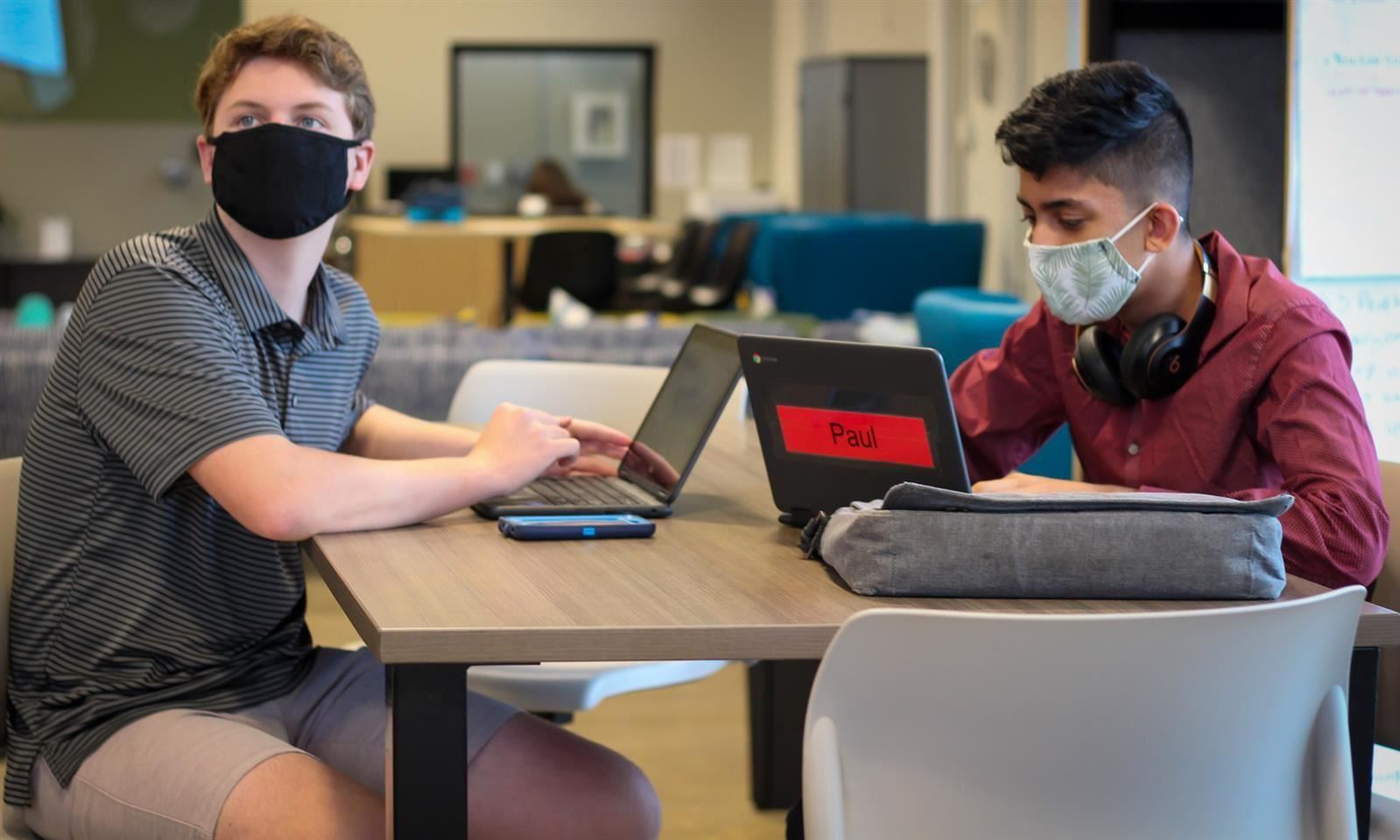 Two students sit at their laptops 