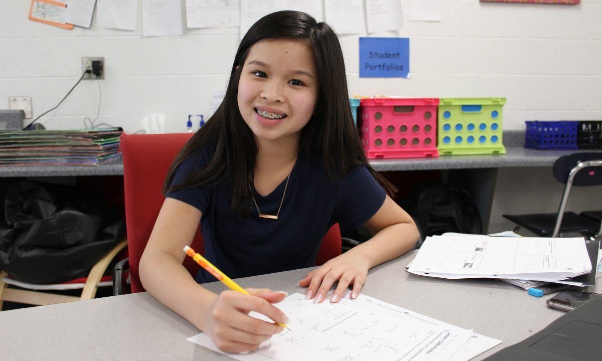 girl sits at desk with pencil 