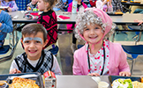 girl and boy dressed as 100 year olds eating lunch in the cafeteria 