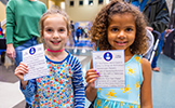  two girls holding up pieces of paper