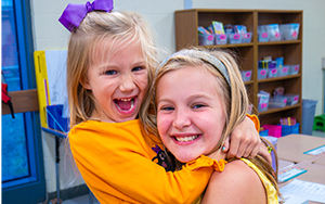  two girls smiling in yellow shirts
