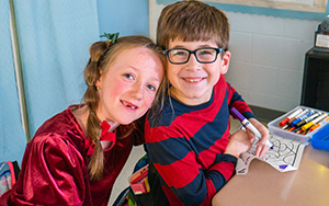  girl and boy smiling while coloring