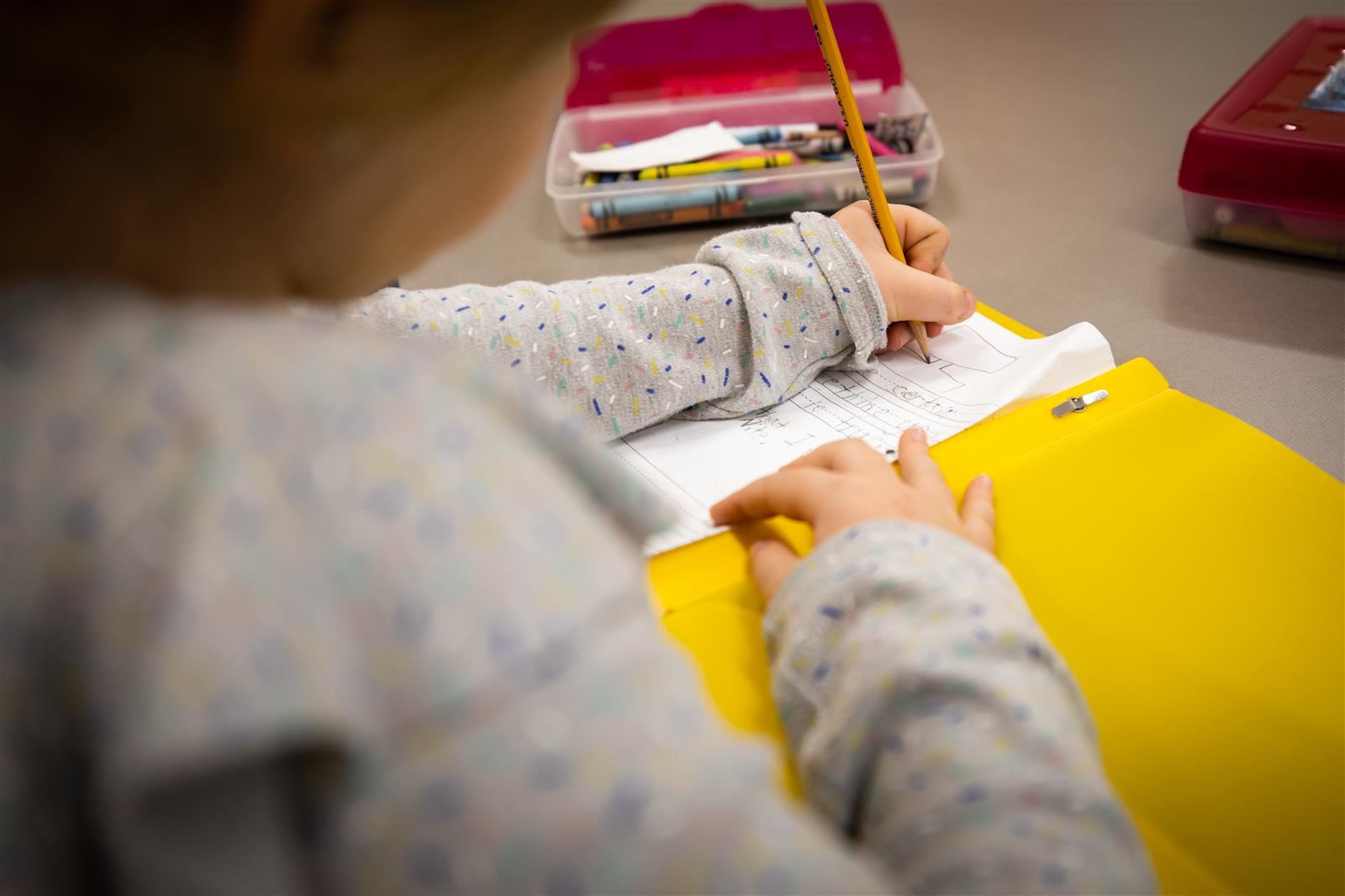 Girl writes with school supplies during class