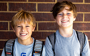  two boys against a brick wall