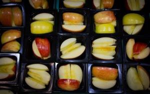   Slices of apples in black trays ready for student lunches.