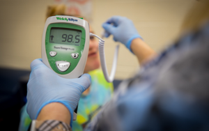  student having temperature taken by school nurse