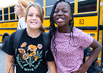  two girls in front of school bus