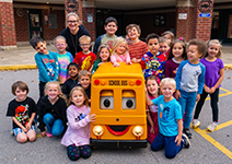  Young elementary students posing with Barney the school bus
