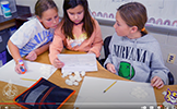  three girls looking at paper and cotton balls