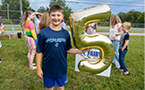 boy holding a 5 balloon 