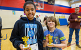  two students in the gym with trophies