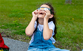  girl looking up wearing eclipse glasses
