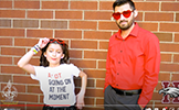  girl and dad in red outfits against a brick wall