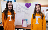two girls in orange sweatshirts 