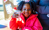 girl in pink jacket with white cup 