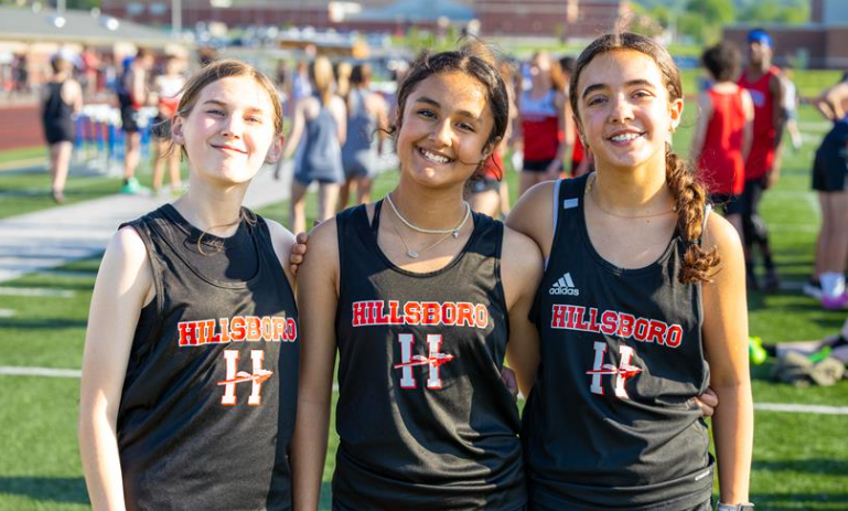 Three female runners smiling at the track meet.