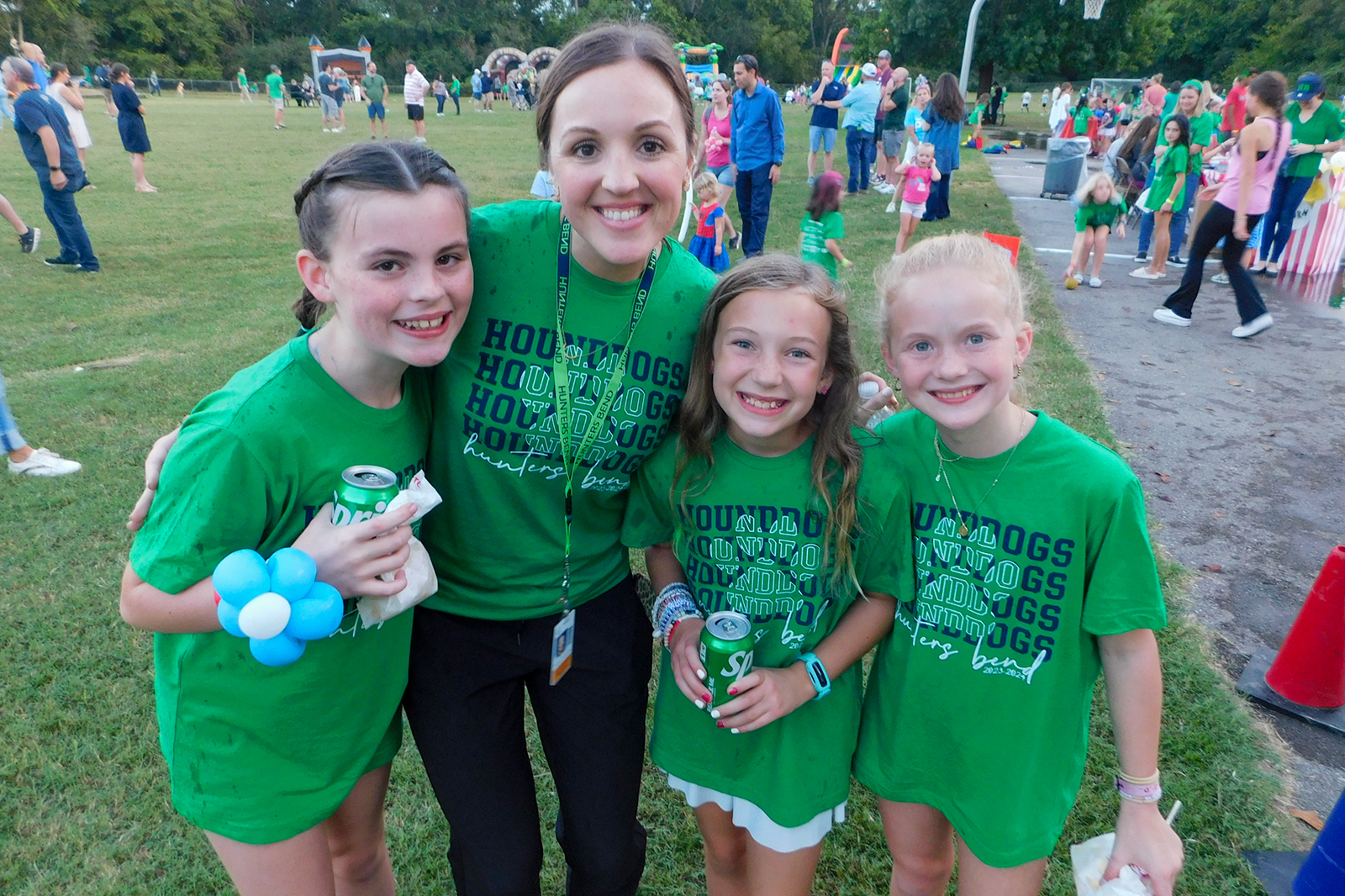 principal and four girls smiling outside in green shirts