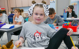 girl dressed as dalmatian dog sitting at her desk