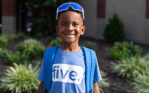  boy smiling with backpack and blue shirt