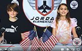  girl and boy at a news desk with american flags