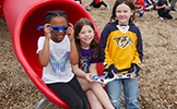  three girls on playground with eclipse glasses