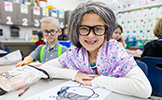  girl in gray wig smiling at desk