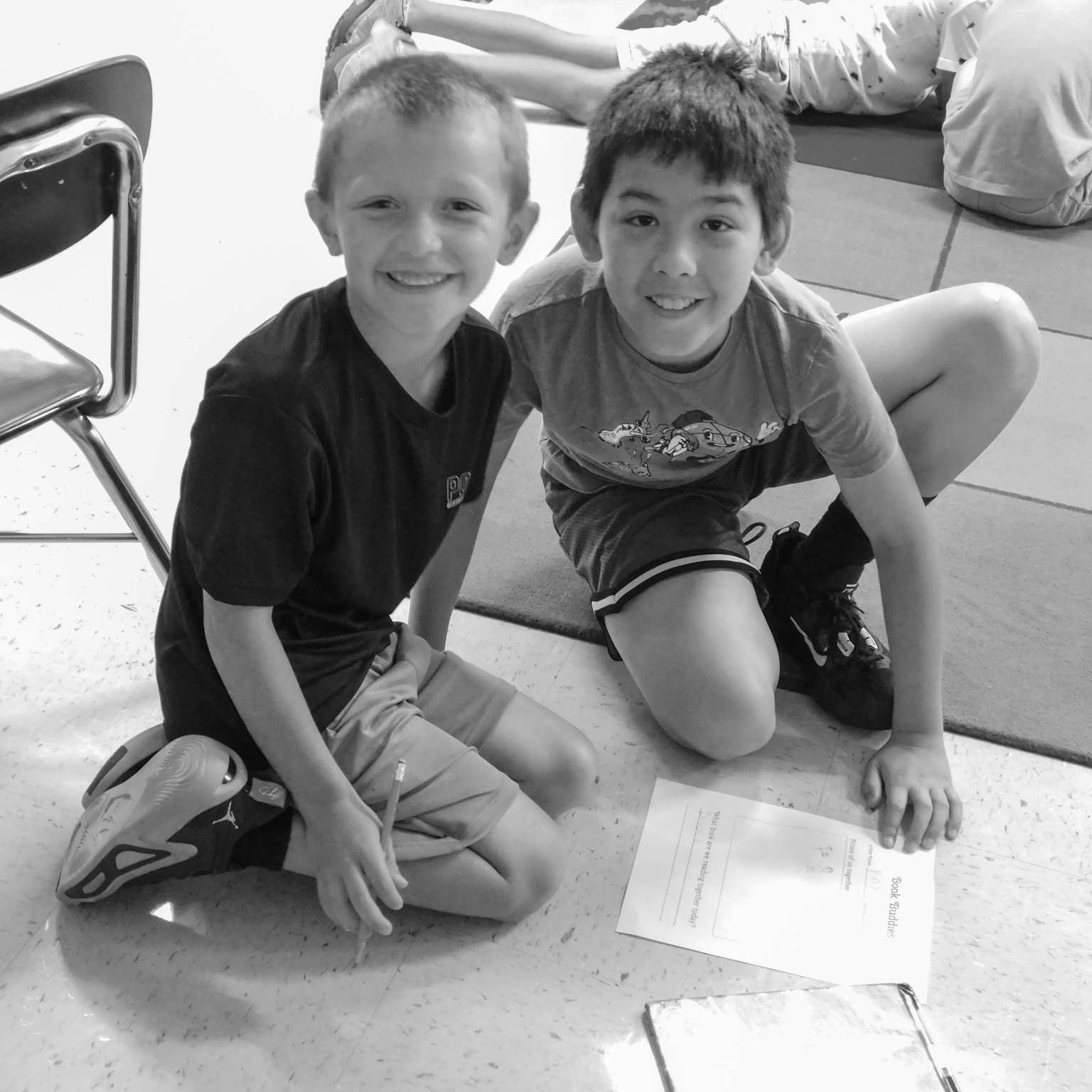two boy smiling with a book