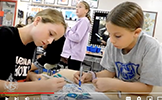  two girls coloring with blue markers
