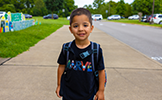  boy walking on sidewalk smiling