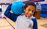  boy holding a bowling ball on his shoulder