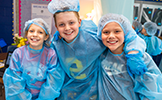  three students smiling wearing scrubs