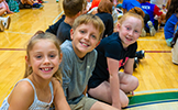  three children sitting on the gym floor
