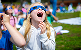  girl with mouth open looking up wearing eclipse glasses