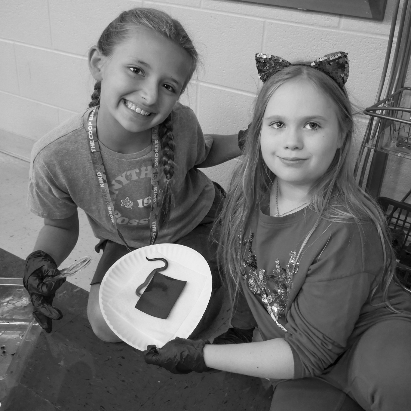 2 girls holding a plate with a worm