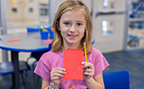 girl holding up red envelope and pencil