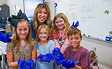  teacher with four students holding worms in blue gloves
