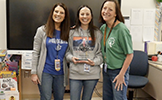 three women standing with trophy 