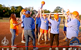  teachers celebrating in a circle on a baseball field