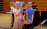  two students holding up colored paper guitars