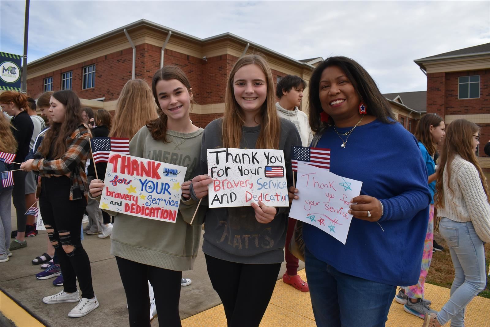 Students and teacher hold Veteran's Day signs