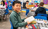 boy at table reading a book 