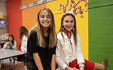  two girls smiling against a rainbow wall