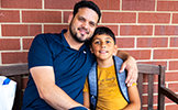  dad and boy student sitting on a bench