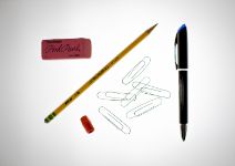 Classroom supplies including paper clips and pencil laying on table