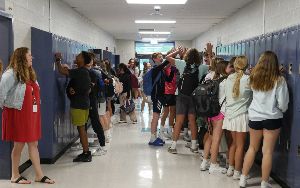  Students are shown at lockers in the hallway between classes